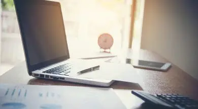 Portrait of businessman with laptop, finance graph and writes on a document at  office.