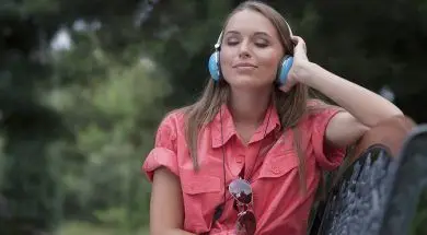 Relaxed young woman listening to headphones on park bench