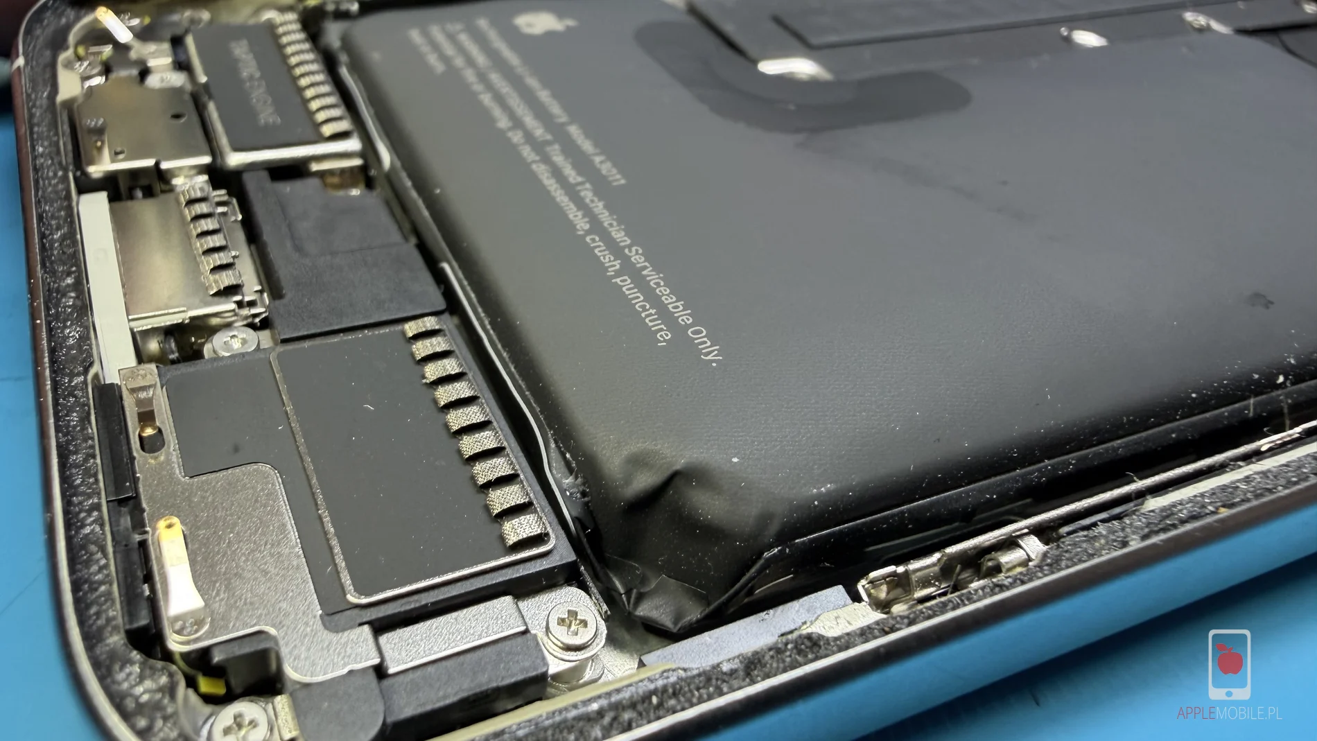 Zużyta spuchnięta bateria po otwarciu obudowy iPhone'a 15 Pro