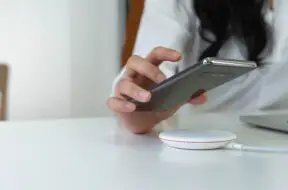 Working Woman putting smartphone on wireless charger in office