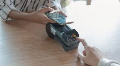 Woman paying bill through smartphone using NFC technology in a coffee. customer paying through mobile phone using contactless technology. Closeup hands of mobile payment at a coffee shop