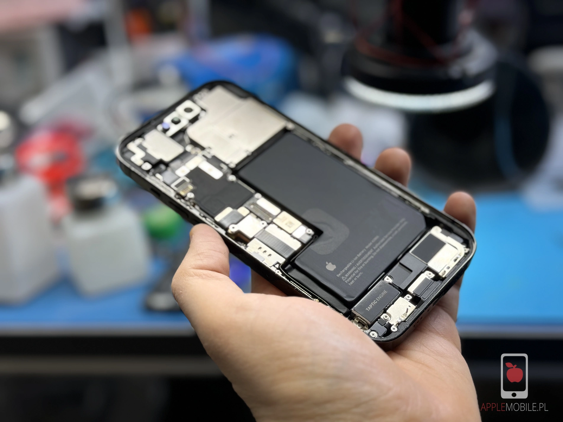 otwarta obudowa iPhone 13 Pro w trakcie wymiany baterii przez pracownika serwisu